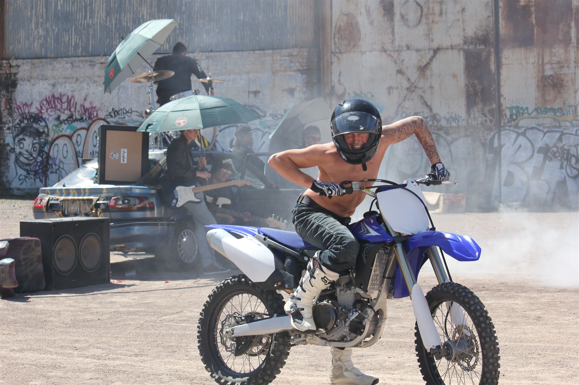 Rider on a dirt bike in front of a graffiti wall at a music video shoot
